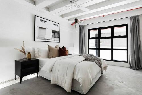 墨尔本New York Converted Warehouse Apartment in Richmond的白色的卧室设有一张大床和一个窗户