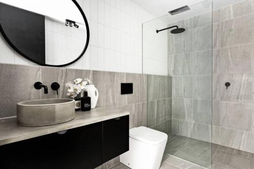 墨尔本New York Converted Warehouse Apartment in Richmond的一间带水槽、卫生间和镜子的浴室