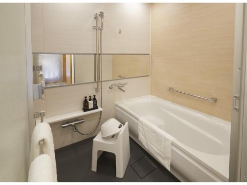 东京TOKYO EAST SIDE HOTEL KAIE的浴室配有白色浴缸和白色凳子