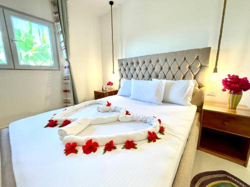 吉汶瓦Manami Villa with Private Pool ZanzibarHouses的卧室配有白色的床铺,上面有红色的鲜花