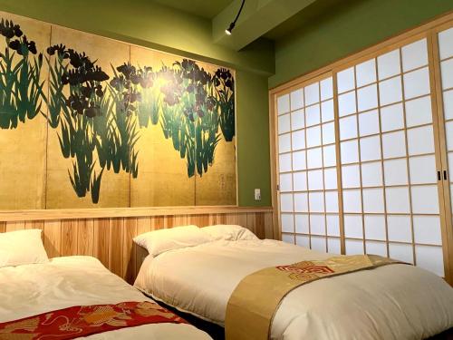 大阪Osaka Ukiyoe Ryokan的墙上画画的房间里设有两张床
