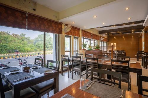 拉明德Hotel Peaceland Lumbini的餐厅设有木桌、椅子和大窗户。