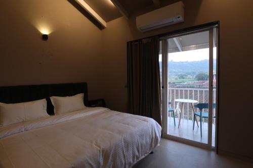 纳西克Isola Luxury Farm Suites的一间卧室配有一张床,阳台配有桌子