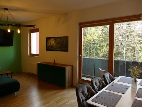 霍茨科波霍尔耶Forest Green Pohorje Apartment的客厅配有桌椅和大窗户