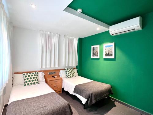 巴塞罗那阿波罗旅馆的一间设有两张床和绿色墙壁的客房