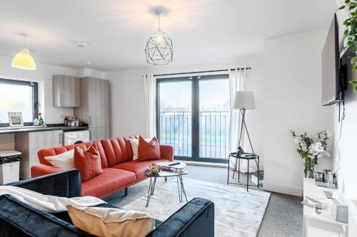 斯劳LiveStay-New Private Apartment Building Minutes From Heathrow的一间带红色沙发的客厅和一间厨房