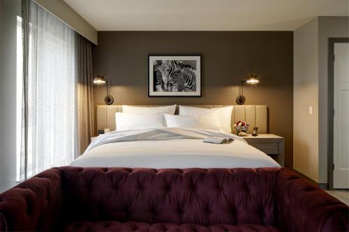 伯灵顿Archer Hotel Boston/Burlington的一间卧室配有一张大床和红色沙发