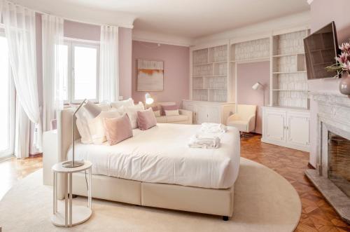 里斯本Luzeiros Suites的卧室配有白色的床和壁炉