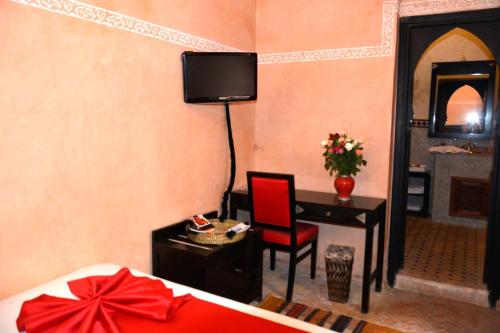 马拉喀什Riad Dar La Rose的一间卧室配有一张床和一张桌子,墙上配有电视