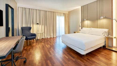 韦尔瓦NH卢斯韦尔瓦酒店的一间酒店客房,配有一张白色的床和一张书桌