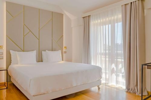 罗马罗马查士丁尼NH系列酒店的一间卧室设有一张大床和一个大窗户