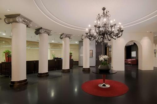 锡耶纳NH锡耶纳酒店的一个带吊灯和红色地毯的大型大堂