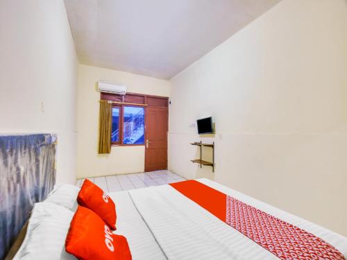 雅加达SUPER OYO 591 Mn Residence Syariah的一间卧室配有一张带红色枕头的床
