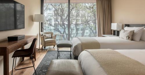 蒙得维的亚Hotel Montevideo - Leading Hotels of the World的酒店客房设有两张床、一张书桌和一个窗户。