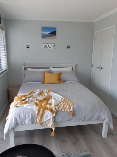PoharaSeascape Hideaway Pohara的卧室配有带橙色枕头的白色床
