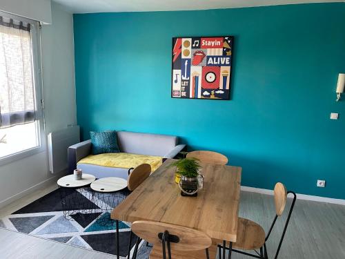 凯恩Grand Studio Lumineux Caen Memorial的客厅配有桌子和蓝色的墙壁