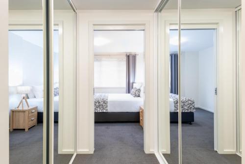 华纳海湾Warners Bay Apartments的一间卧室配有两张床和两面镜子