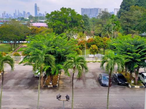 吉隆坡Pusat Belia Antarabangsa的停车场有停放的汽车和棕榈树