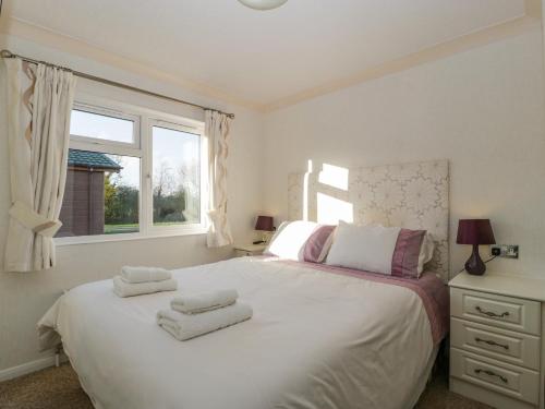 PuxtonHarvester Lodge的卧室配有白色的床和2条毛巾