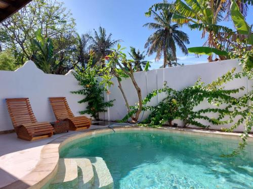 吉利特拉旺安Cantika Villa的庭院内的游泳池,配有两把椅子和树木