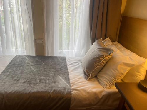 伦敦卡文迪什酒店的窗户前带枕头的床