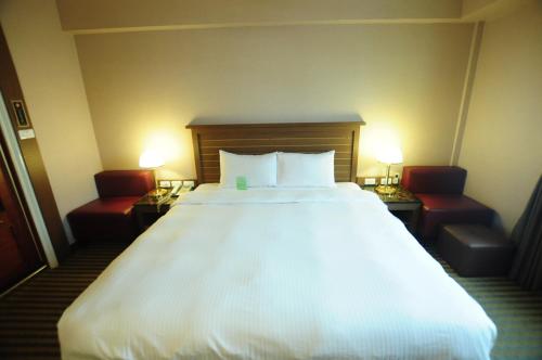 台东康桥商旅-台东馆的一张大白色床,位于酒店客房内,配有两把椅子