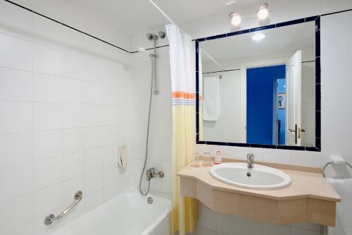 奇克拉纳－德拉弗龙特拉索尔桑克蒂佩特里公寓式酒店的一间带水槽、浴缸和镜子的浴室