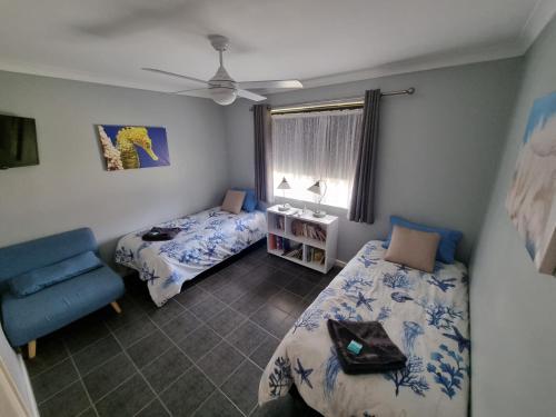 朱里恩湾海洋沙滩木屋18的一间卧室设有两张床、一把椅子和一个窗户。