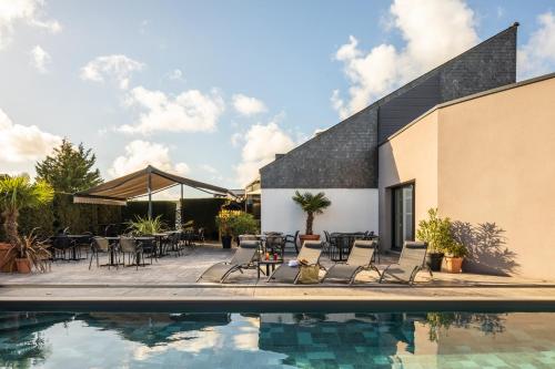 特里尼亚克宜必思圣纳扎尔特里纳克酒店的一座带桌椅的游泳池位于大楼旁