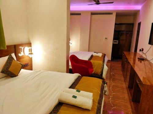 瓦拉纳西Namaste Benares Varanasi的酒店客房,设有两张床和一张红色椅子