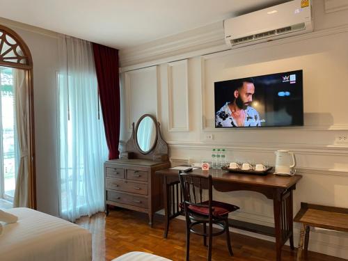 清迈Wiang Ville Boutique Hotel的酒店客房设有一张桌子和一台墙上的电视。