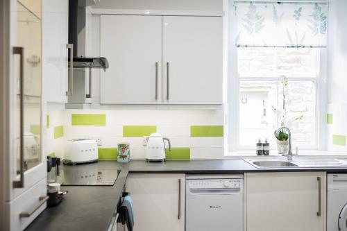StaindropThe Old Packhorse的厨房配有白色橱柜和绿色及白色条纹