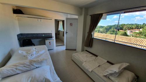 卡皮托利乌Hotel Escarpas do Lago Capitolio的一间卧室设有两张床和大窗户