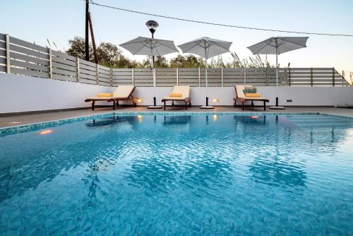 马斯蒂查里Seabreeze Villa - with Jacuzzi & heated pool的一座大楼内的游泳池,配有椅子和遮阳伞