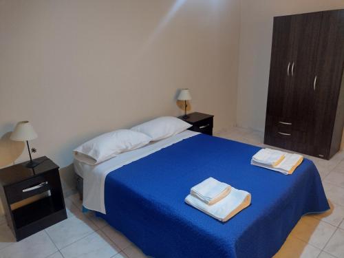 图努扬La Candida的一间卧室配有蓝色的床和2条毛巾