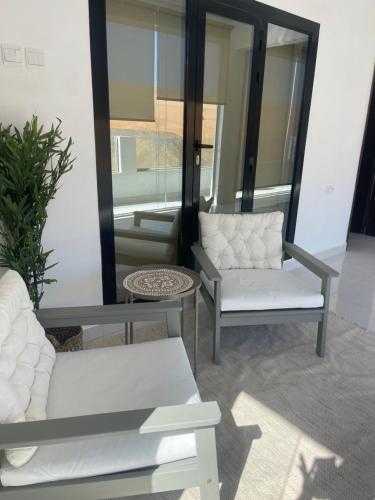 Al WāşilHome X4的客厅配有两把白色椅子和镜子