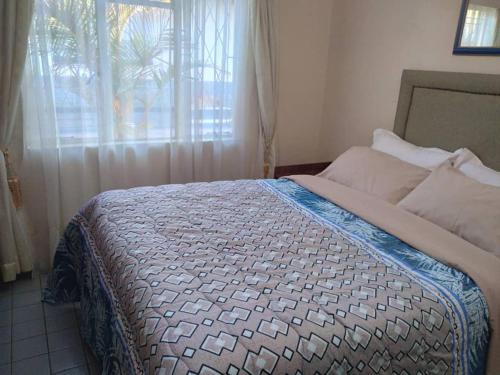 哈拉雷Beautiful 2-Bedroomed Guest Cottage in Harare的一间卧室设有一张大床和窗户