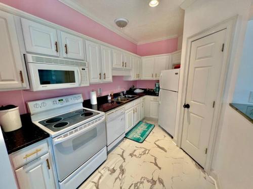 默特尔比奇Lovely Home Near Myrtle Beach的设有带白色家电和粉红色墙壁的厨房
