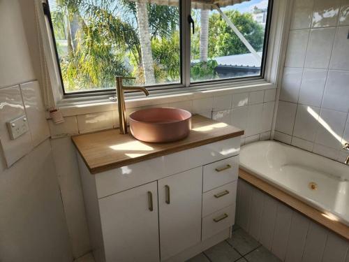 布里斯班Classic Brisbane Queenslander with Pool & Yard的一间带水槽和浴缸的浴室以及窗户。
