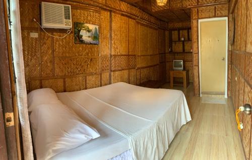 波尔多·格尼拉Bamboo House Beach Lodge & Restaurant的卧室配有一张白色的木墙床