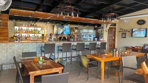 邦劳阿罗那珊瑚花园度假村服务式公寓的一间带木桌椅的餐厅和一间酒吧
