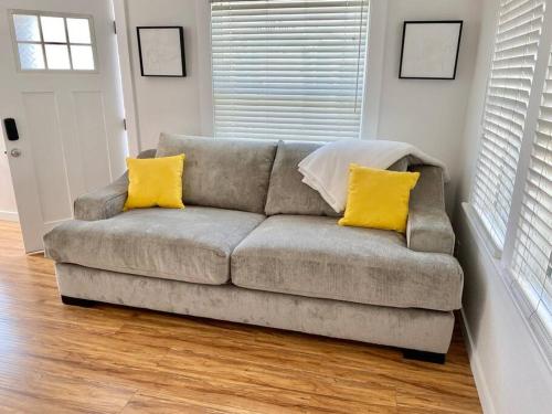 长滩LBC Paradise Bungalow的客厅里一张带两个黄色枕头的沙发