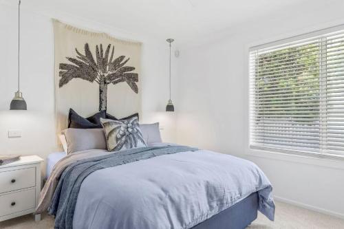 文森提亚Swell Jervis Bay的卧室配有一张床铺,墙上挂着棕榈树