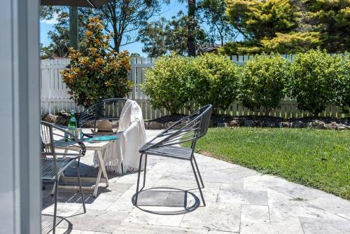 文森提亚Swell Jervis Bay的庭院配有两把椅子、一张桌子和一把遮阳伞