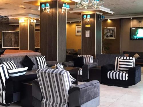 埃尔比勒Hotel Sinaia Palace的一间设有黑白椅子和电视的等候室