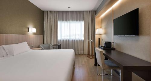 马德里NH马德里里贝拉格兰德曼萨纳雷斯酒店的配有一张床和一张书桌的酒店客房