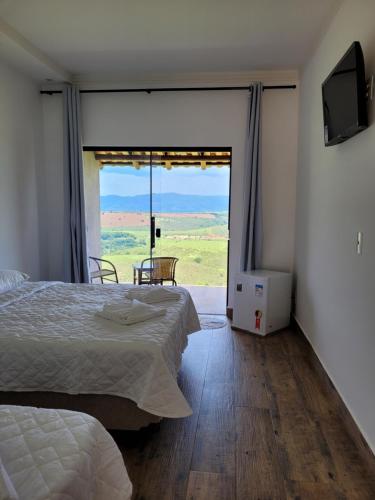 圣罗克迪米纳斯Pousada Colina da Canastra的一间卧室设有一张床和一个滑动玻璃门
