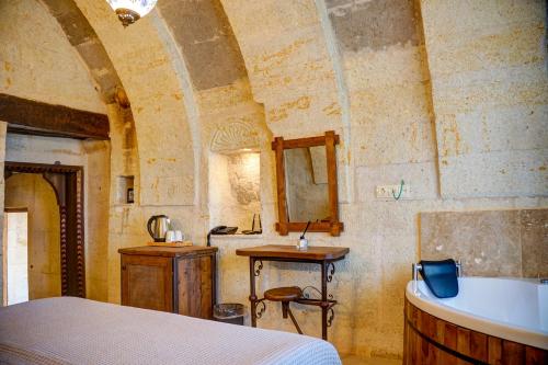 乌奇希萨尔Karma Suites Cappadocia的一间卧室配有一张床和一个水槽和一个浴缸