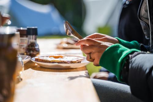 西泰尔斯海灵BlueCAMP Oerol24- Tent&Breakfast的坐在餐桌上吃一盘食物的人