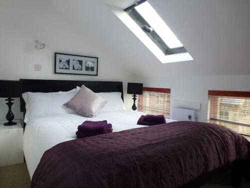 萨默福德凯恩斯The Stables, Lower Mill Estate的卧室配有一张大白色床和紫色床单